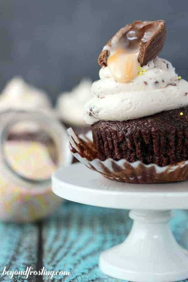A close up shot of a gooey Cadbury egg dripping onto a frosted cupcake