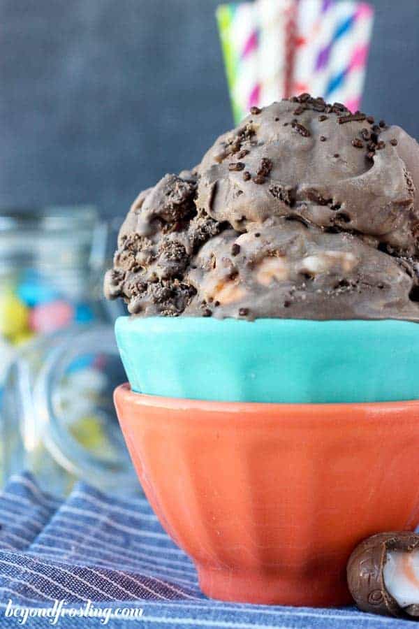 A close up of two bowls, teal and red with a heaping scoop of chocolate ice cream in it