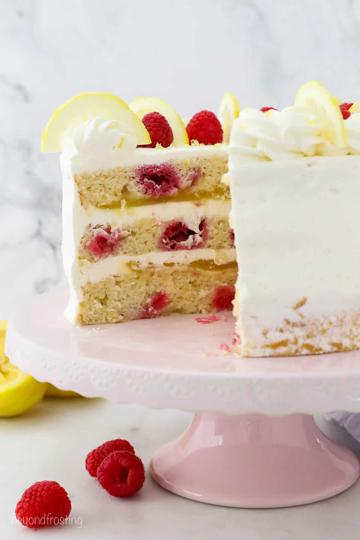 A lemon raspberry layer cake with a slice missing