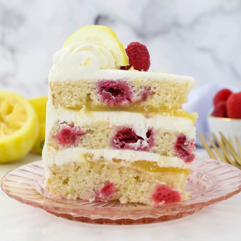 A slice of lemon raspberry cake on a pink plate.