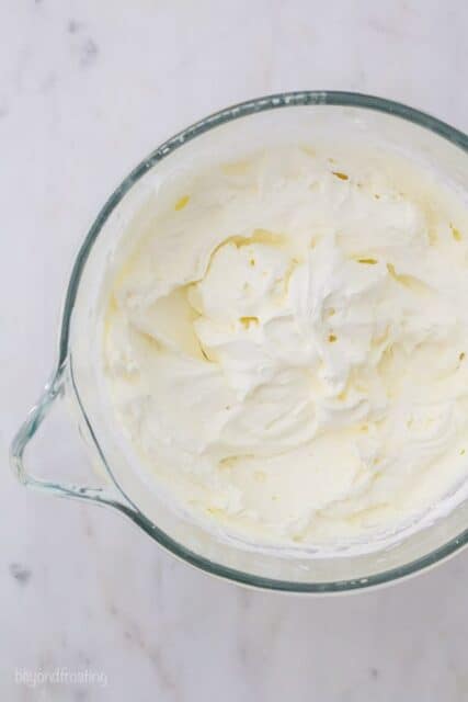 An overhead shot of a glass mixing bowl with a whisk filled with Mascarpone Whipped Cream