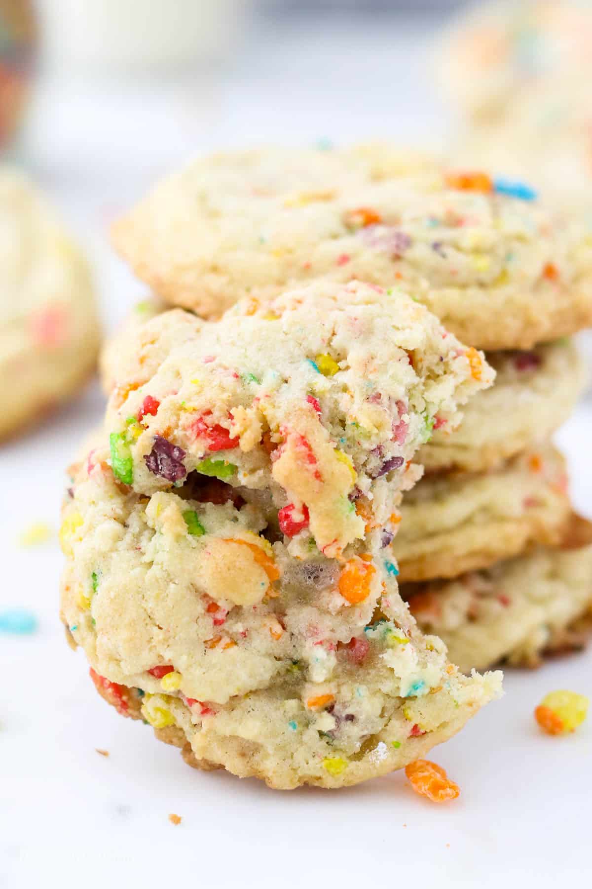 A half eaten fruity pebble cookie leaning up against others