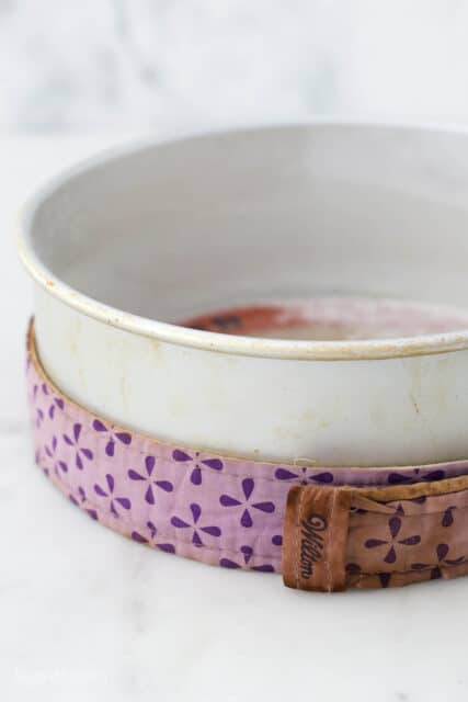 A lined baking pan wrapped with a purple bake-even strip.