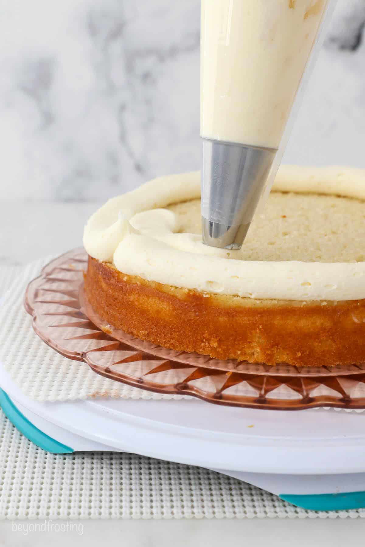 A cake scraper smoothes out the crumb coat on a double-layer cake.