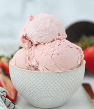 A polka dot bowl with 3 scoops of strawberry ice cream