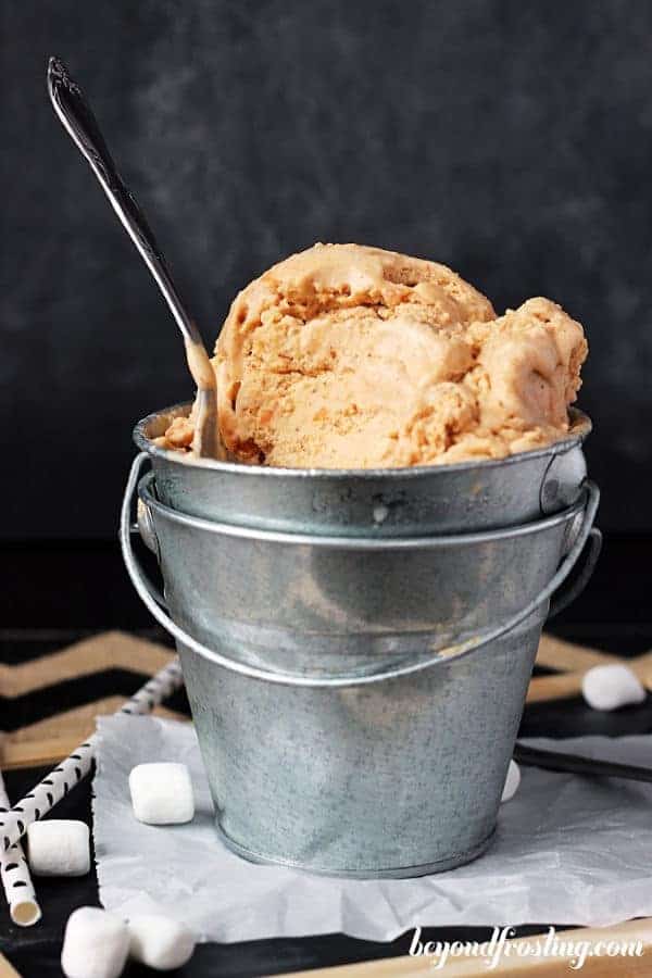 a silver bucket with sweet potato ice cream and a spoon in it, a couple bites missing