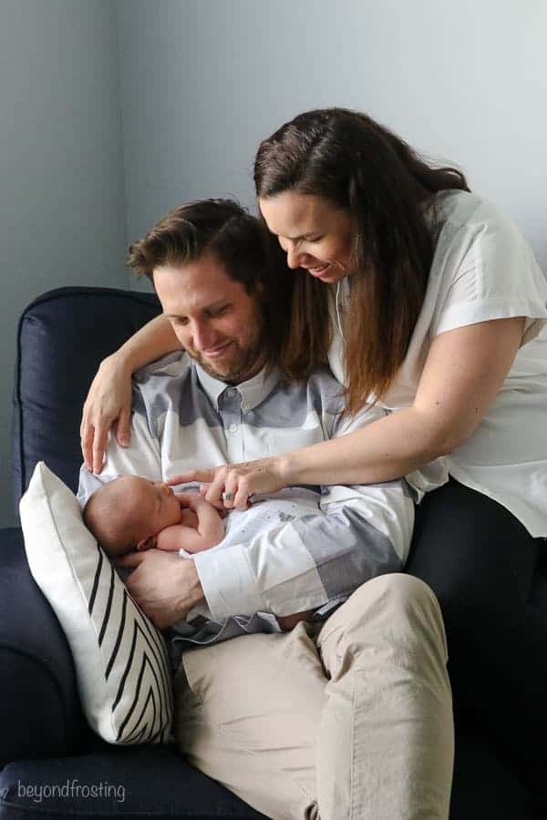 A mom and dad looking at their newborn sitting in a rocking chair