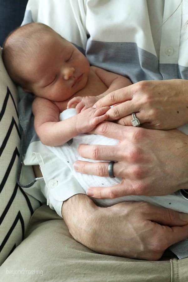 mom and dads hands laid over babys hands