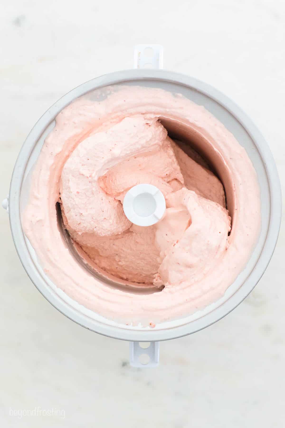 Overhead view of strawberry ice cream churning inside the ice cream maker.