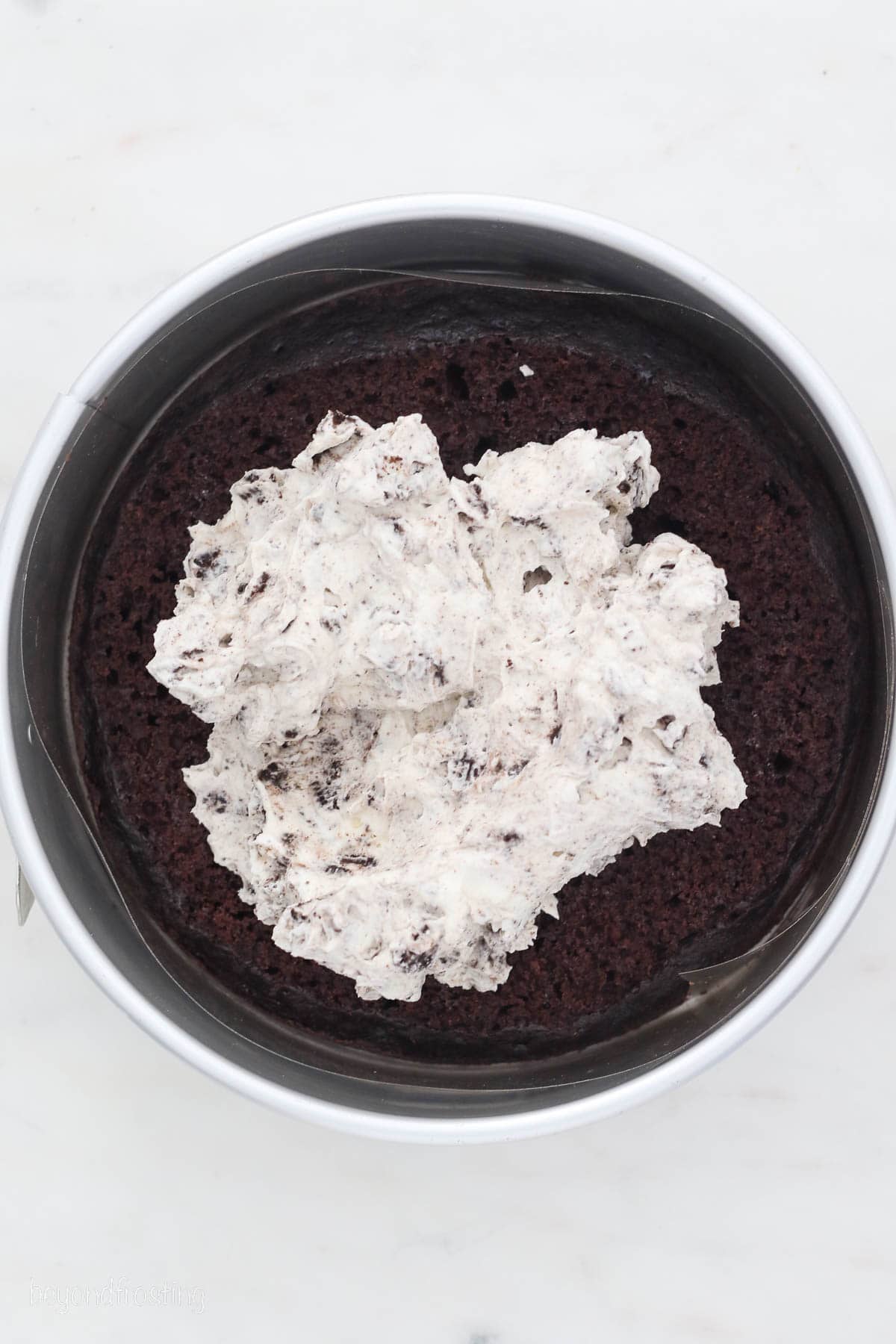 Oreo ice cream added over top of chocolate cake in a springform pan.