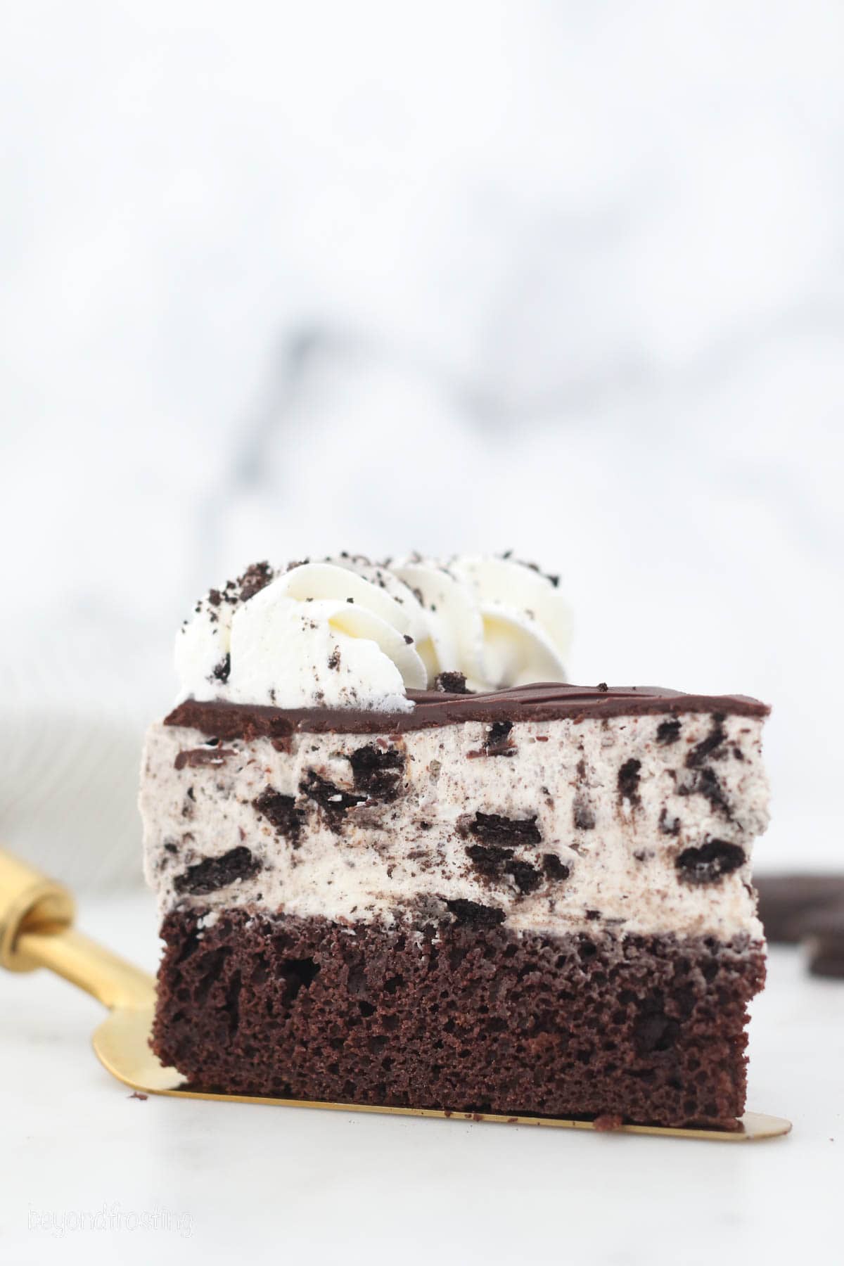 A slice of Oreo ice cream cake topped with whipped cream.