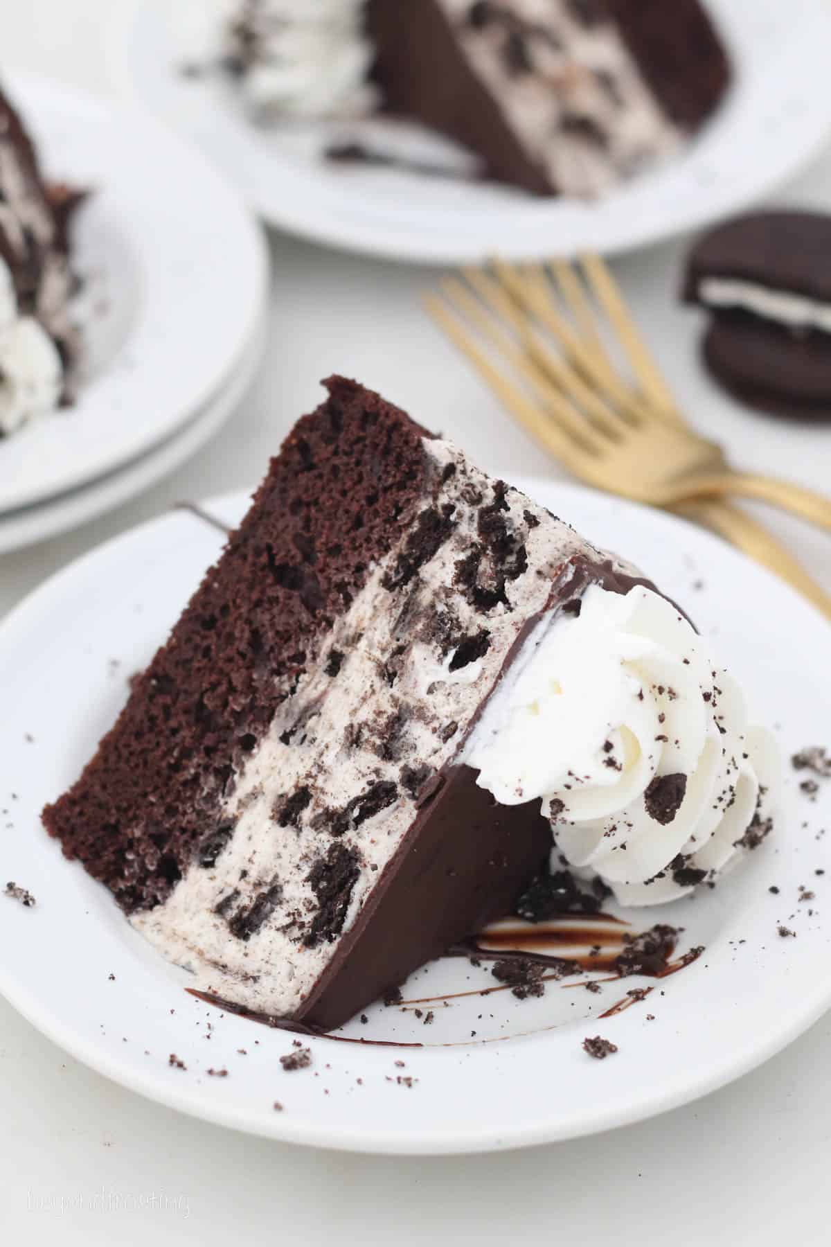 A slice of Oreo ice cream cake on its side on a white plate.