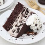 A slice of Oreo ice cream cake on its side on a white plate.