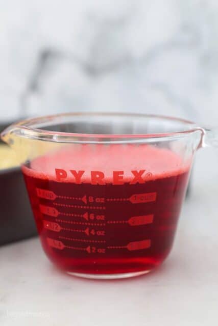 a glass measuring cup with red jello mix