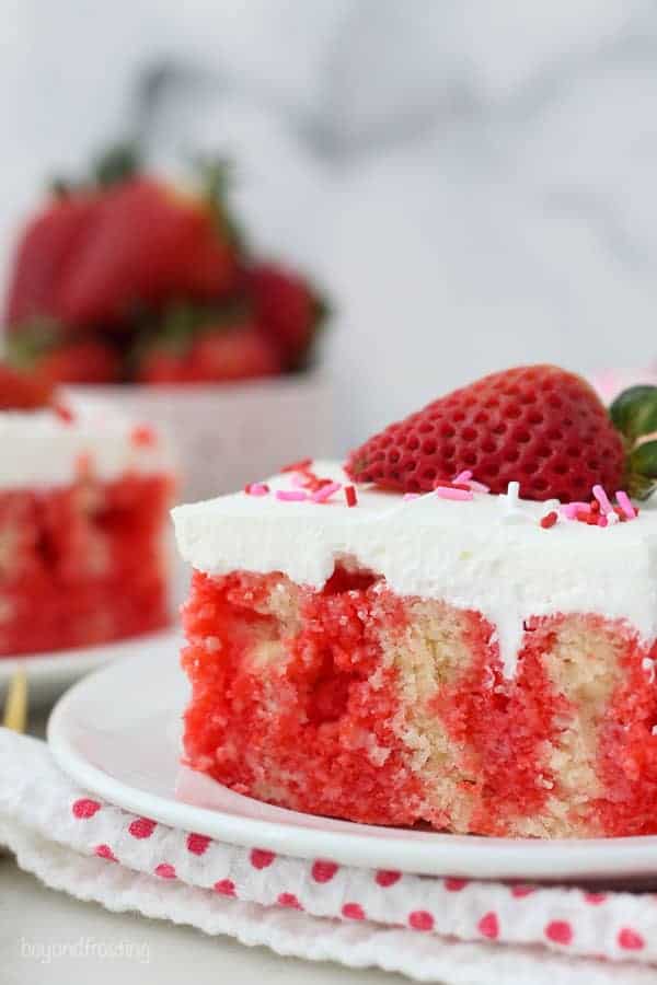 A close up shot of a slice of jello poke cake, showing the red jello inside the cake