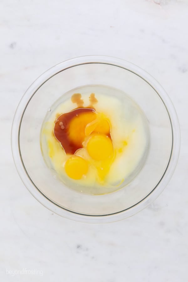 an overhead shot of chocolate cake batter, eggs and vanilla in the bowl