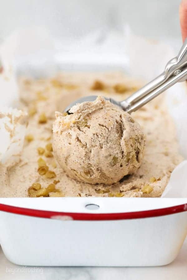 An ice cream scoop scooping through a pan of ice cream