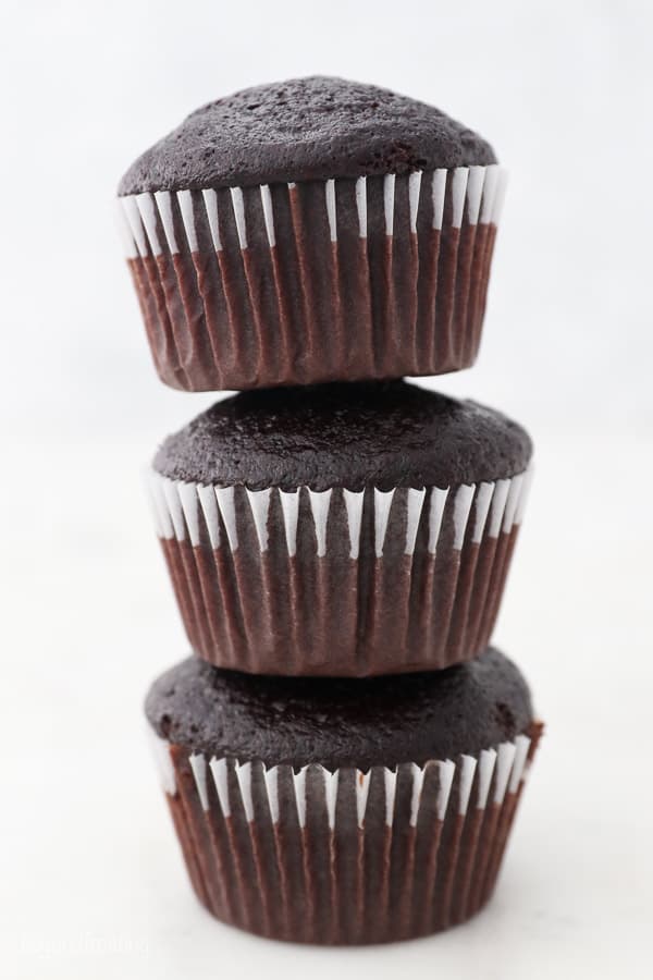 three unfrosted chocolate cupcakes stacked