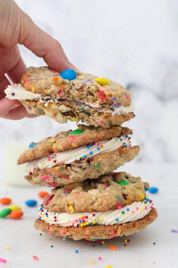 A stack of three cookie sandwiches with vanilla buttercream, the one on top had a bite taken out of it