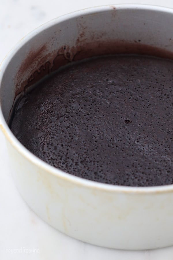 a side view of a baked chocolate cake layer in a metal pan