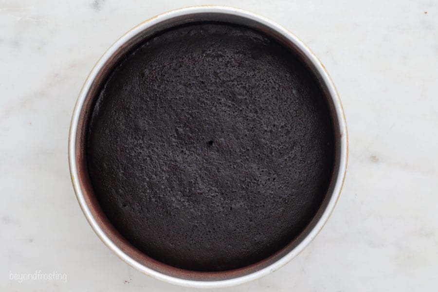 A wide angle shot of a baked chocolate cake layer in a metal pan