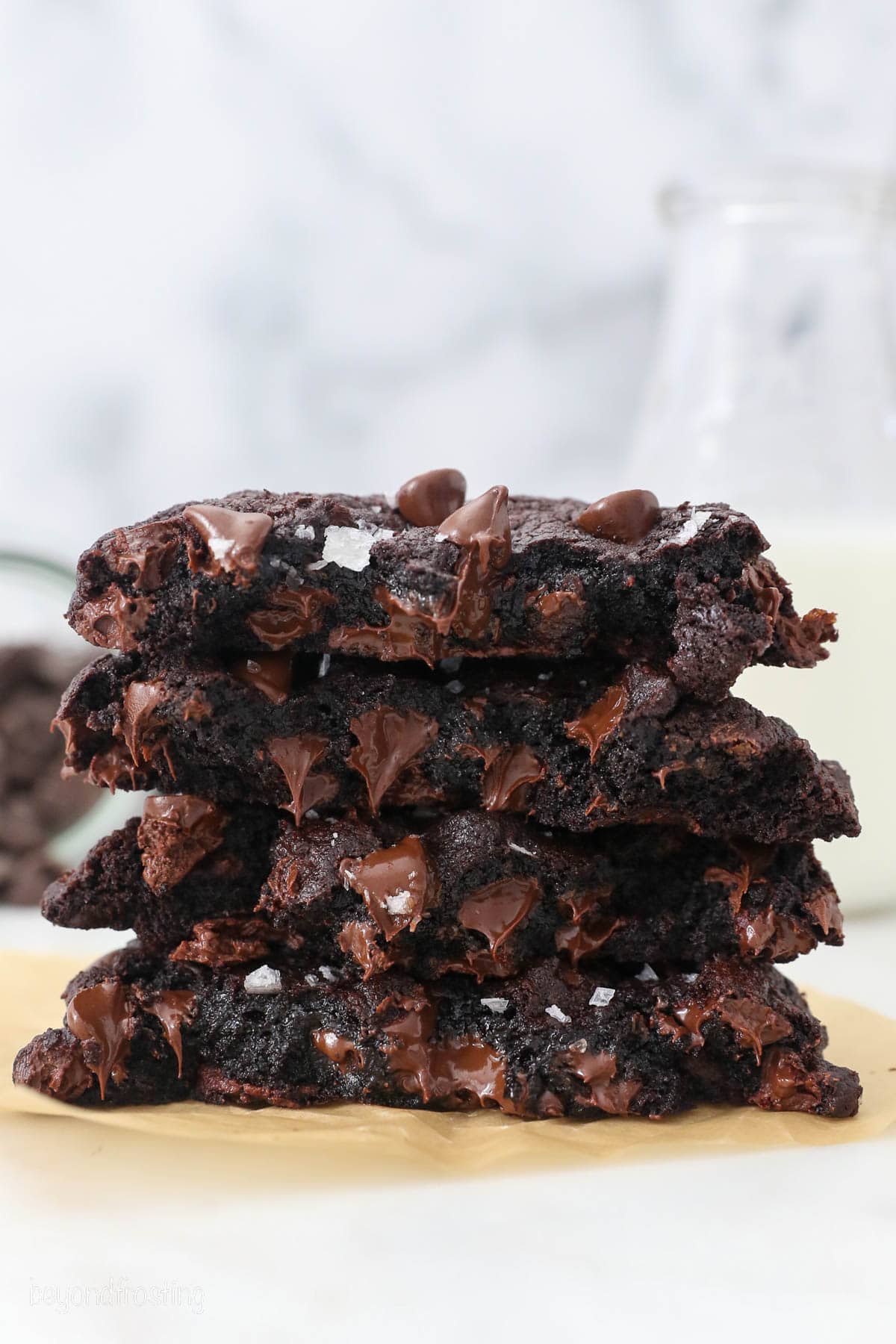 A stack of chocolate cookie halves on a piece of parchment paper.