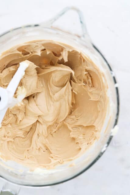 Creamy peanut butter frosting in a stand mixing bowl with the whisk attachment.