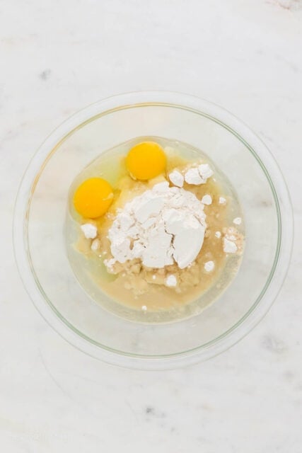 Eggs added to dry ingredients in a glass bowl.