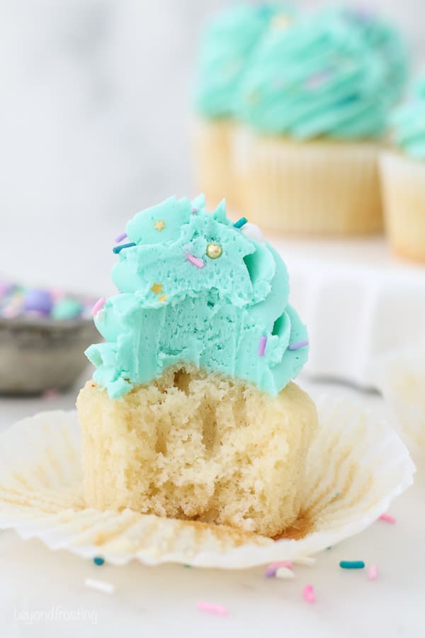 A cupcake with teal frosting has a bite taken out of it
