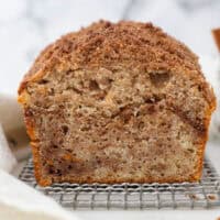 Front view of a loaf of cinnamon apple bread on a wire rack, sliced to reveal the cinnamon streusel swirled inside.