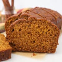 Front view of a loaf of pumpkin bread cut into slices on a piece of parchment paper.