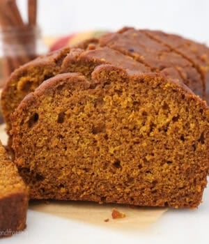 Front view of a loaf of pumpkin bread cut into slices on a piece of parchment paper.