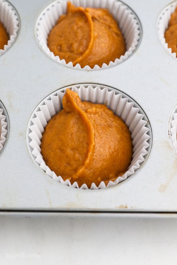 a close up of pumpkin muffin batter in a muffin pan