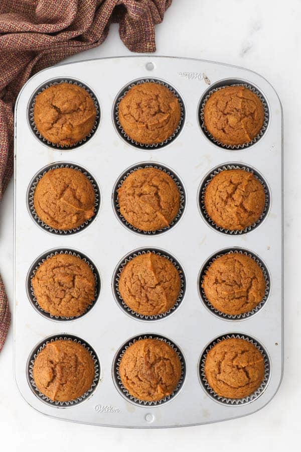 an overhead shot of 12 pumpkin muffins in a muffin pan