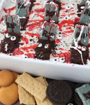 A halloween themed graveyard dip with cookies and crackers next to it