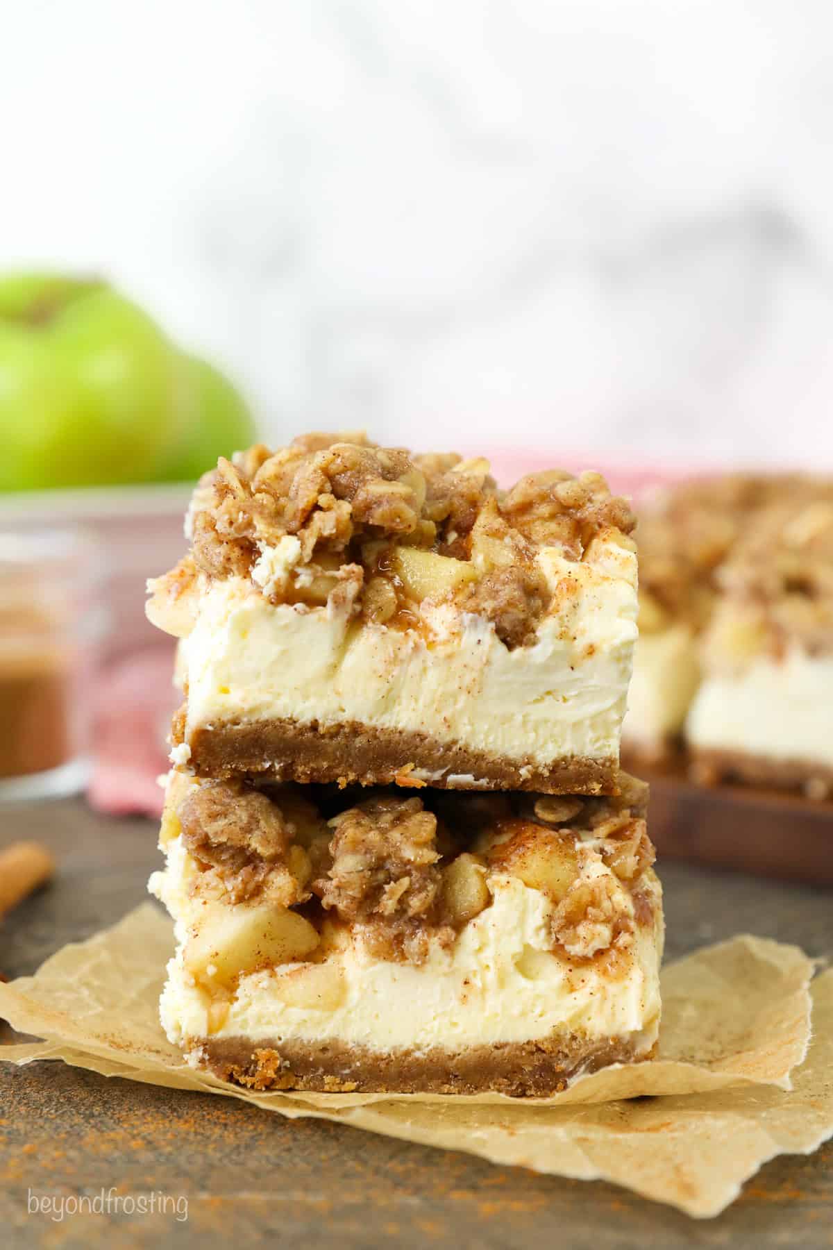 Two caramel apple cheesecake bars stacked on top of one another.