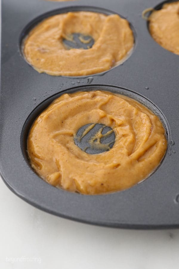 a side view of pumpkin donut batter in a donut pan