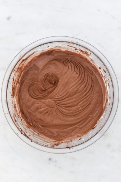 Whipped chocolate cheesecake batter in a glass mixing bowl.