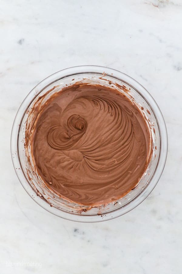 a glass mixing bowl with chocolate cheesecake batter