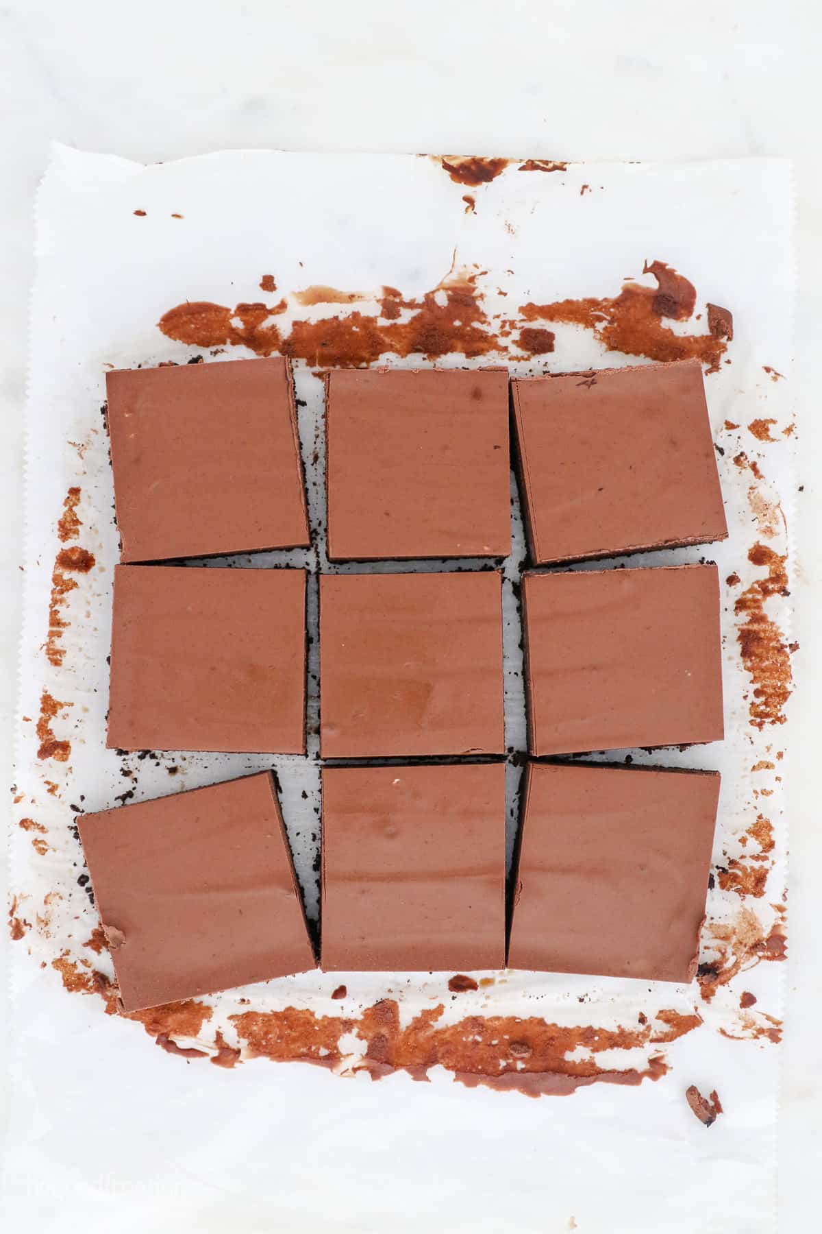 Overhead view of sliced chocolate cheesecake bars on top of a piece of parchment paper.