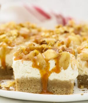 Apple cheesecake bars on a plate with dripping caramel