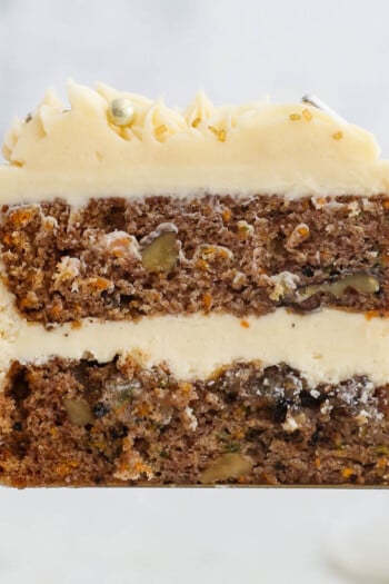 A slice of frosted sweet potato cake lifted up with a cake server.