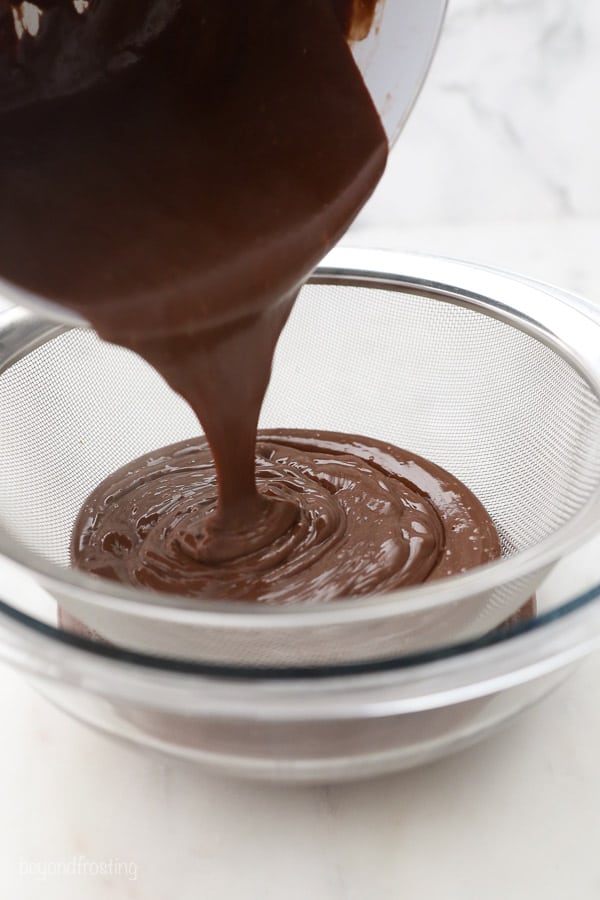 chocolate pudding being poured through a mesh sieve