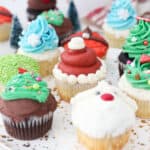 Assorted Christmas cupcakes decorated with buttercream Christmas trees, Santa, and reindeer.