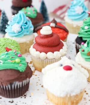 Assorted Christmas cupcakes decorated with buttercream Christmas trees, Santa, and reindeer.