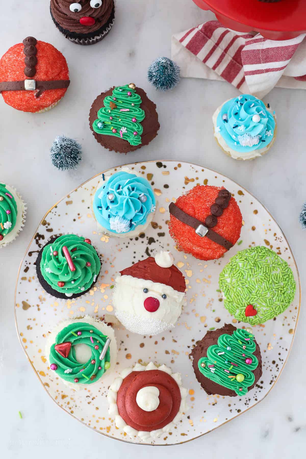 Overhead view of Assorted Christmas cupcakes decorated to look like Christmas tees, Santa, reindeer, and more.