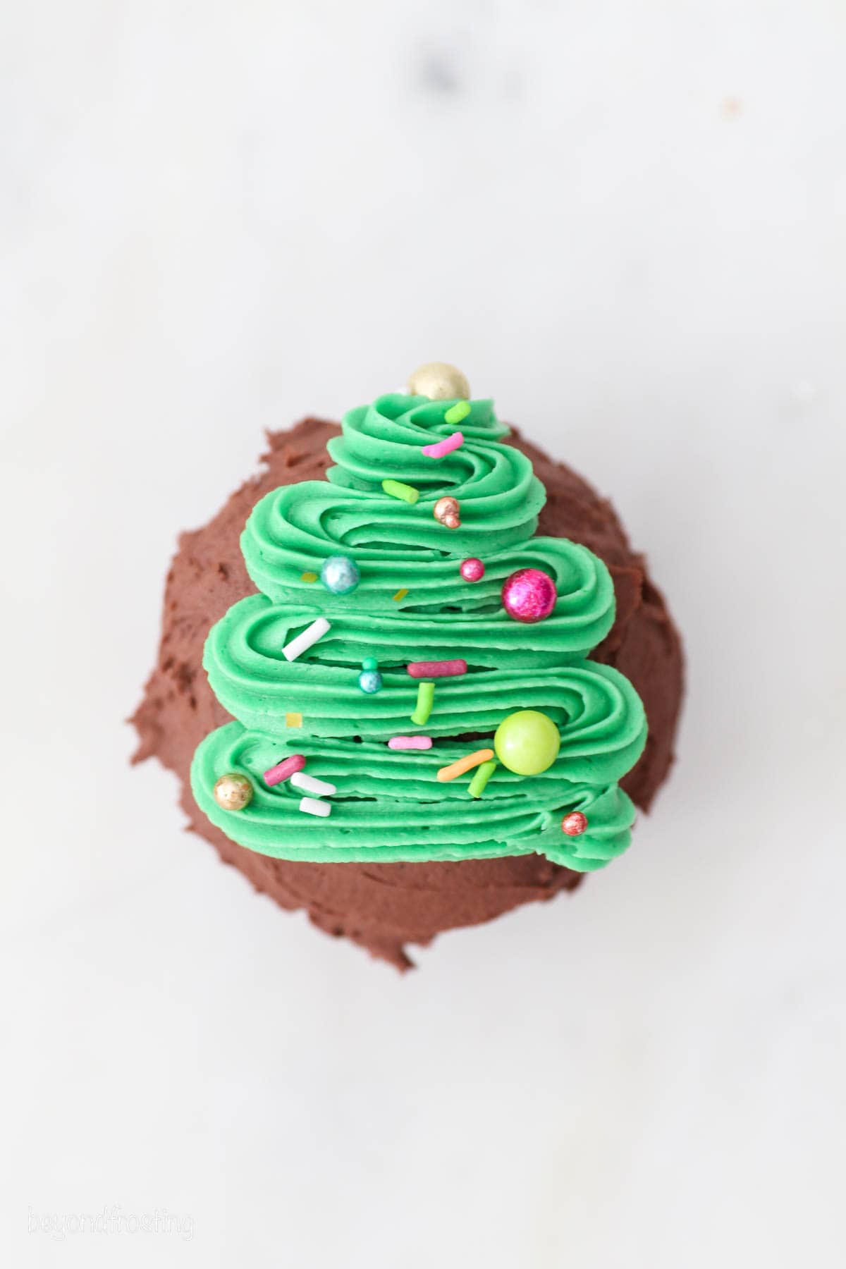 Overhead view of a cupcake frosted with a buttercream Christmas tree.