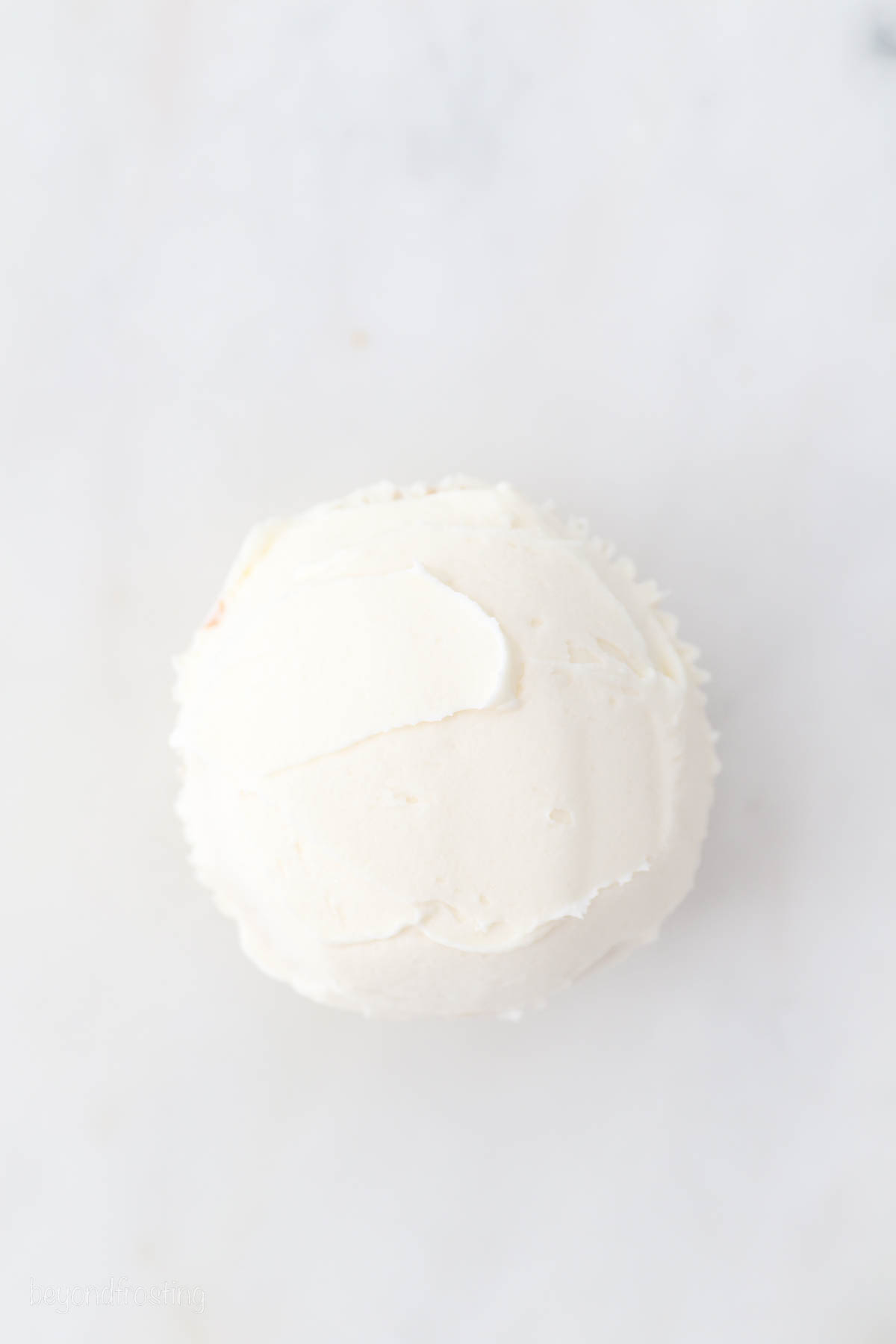Overhead view of a cupcake frosted with white buttercream frosting.