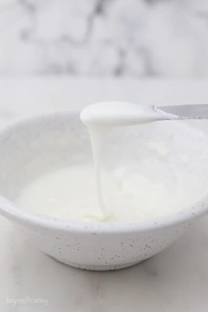 a bowl of white icing with a knife