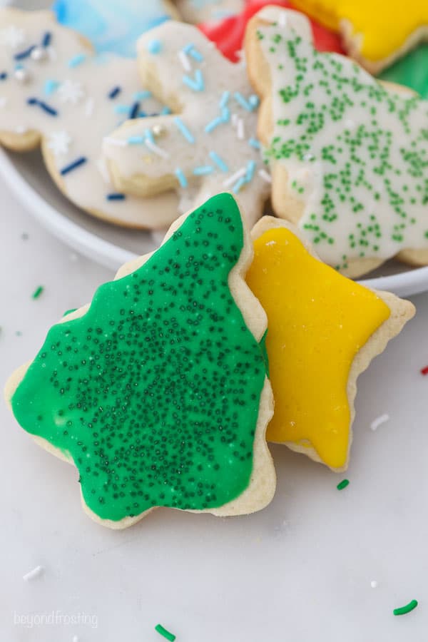 A Christmas tree shaped cookie with sprinkles and a yellow star cookie